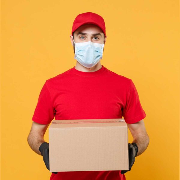 A delivery man wearing gloves and holding a box.